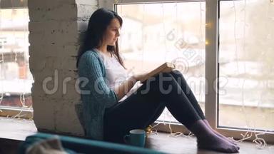 美丽的女孩正在看<strong>书</strong>，<strong>翻书</strong>页坐在窗户上，有时看着窗外。 文学